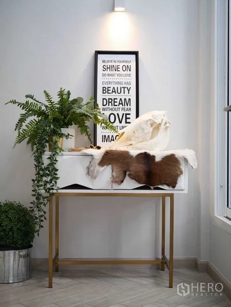 Townhouse for rent in Watthana, Bangkok - Stylish entry console with wall art and indoor plants under a spotlight.