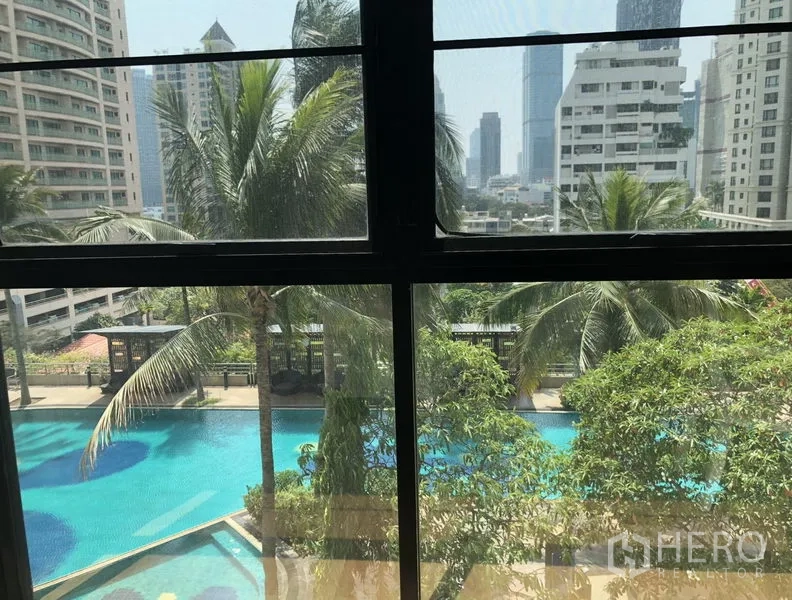 Condominium for rent or sale in Sathon, Bangkok - Window view of resort-style swimming pool, palm trees and Bangkok skyline.