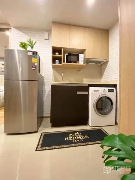 Condominium for sale in Ratchathewi, Bangkok - Compact condo kitchenette with stainless fridge, upper cabinets, microwave, range hood, and in-unit front-load washer.