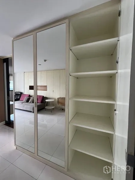 Condominium for rent or sale in Khlong Toei, Bangkok - Mirrored wardrobe and open shelving unit near the living area.