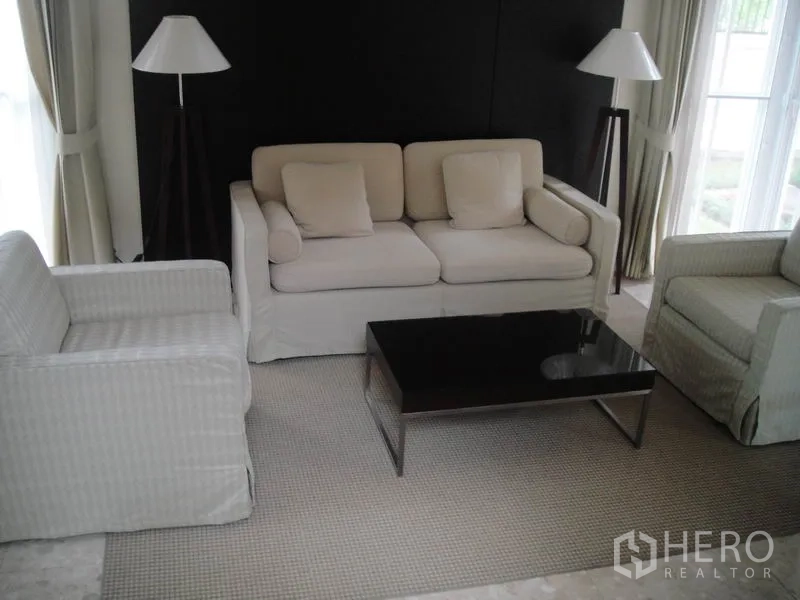 Detached House for rent in Wang Thonglang, Bangkok - Cozy sitting area with cream sofa set, dark feature wall and glass coffee table.