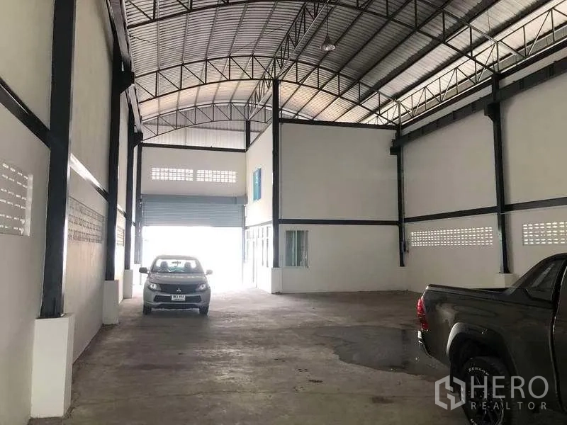 Warehouse for rent in Pak Kret, Nonthaburi - Deep warehouse aisle with high ceiling, roller shutter door and ventilation block walls.