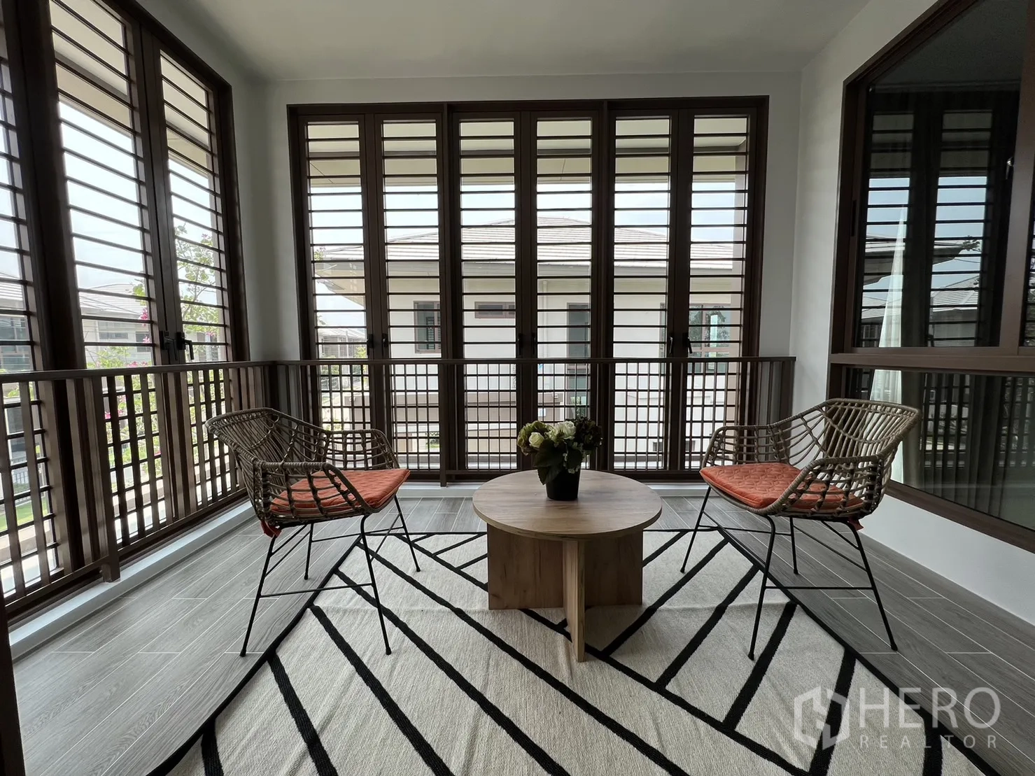 Detached House for rent in Bang Kapi, Bangkok - Enclosed balcony sunroom with louvered windows and seating set.