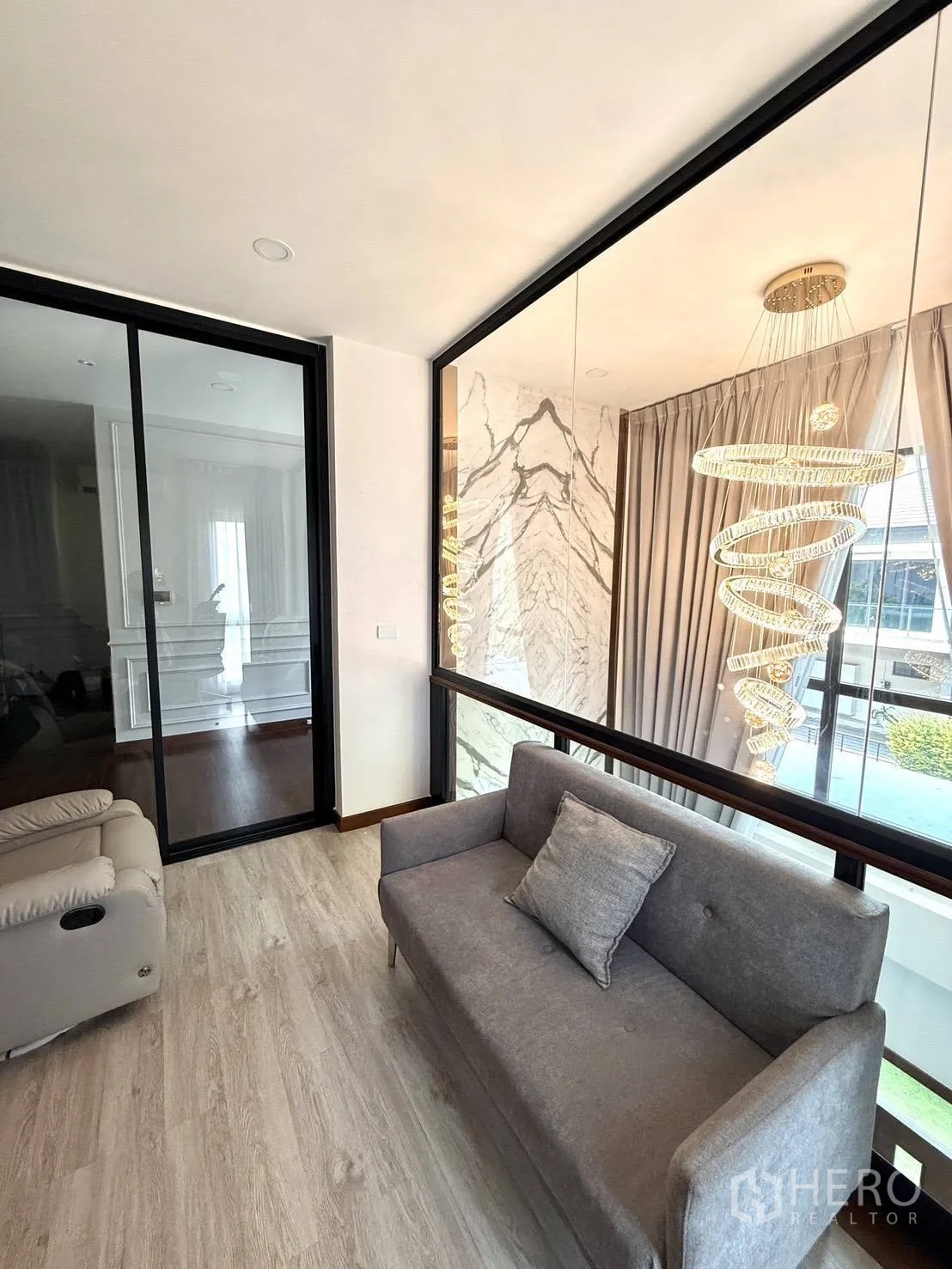 Detached House for rent in Wang Thonglang, Bangkok - Upstairs landing lounge with a sofa beside a glass wall overlooking the foyer.