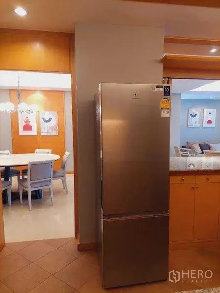 Apartment for rent - Stainless steel refrigerator with view to a dining area featuring a round table and pendant lights.