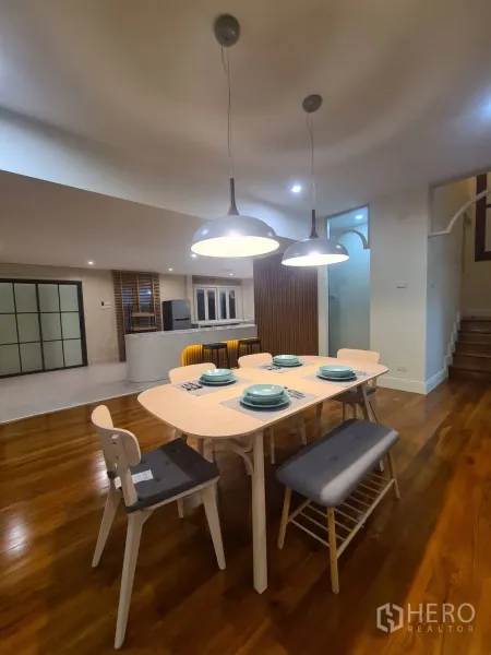 Detached House for rent in Khlong Toei, Bangkok - Modern dining area with wooden table, pendant lights and an open kitchen.
