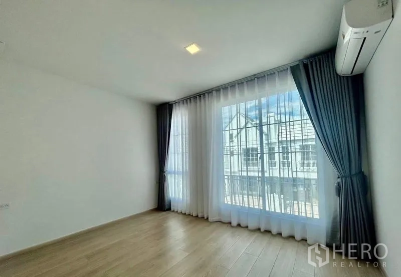 Townhouse for rent in Bang Phli, Samut Prakan - Sunlit master bedroom with floor-to-ceiling windows, sheer drapes and wall AC.