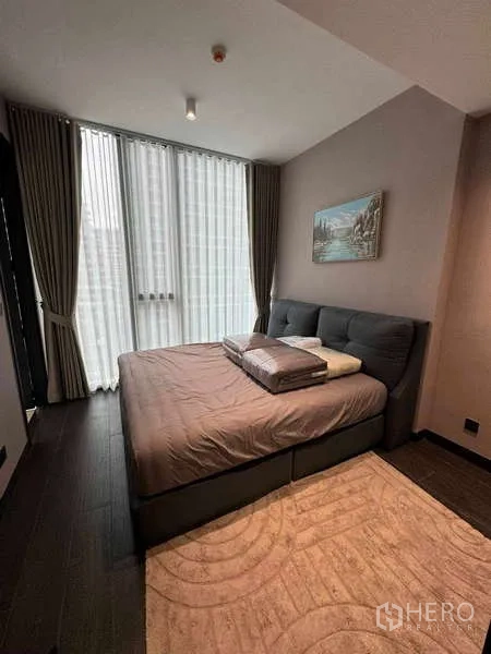 Condominium for rent in Bang Rak, Bangkok - Master bedroom with floor-to-ceiling curtains and an upholstered bed