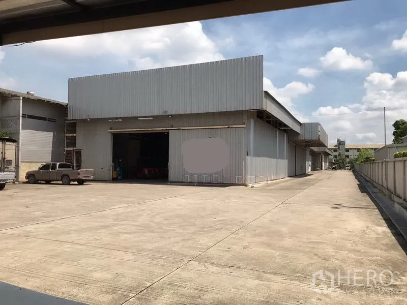 Warehouse for rent in Mueang Samut Sakhon, Samut Sakhon - Front yard with wide concrete apron and loading bay of metal warehouse.