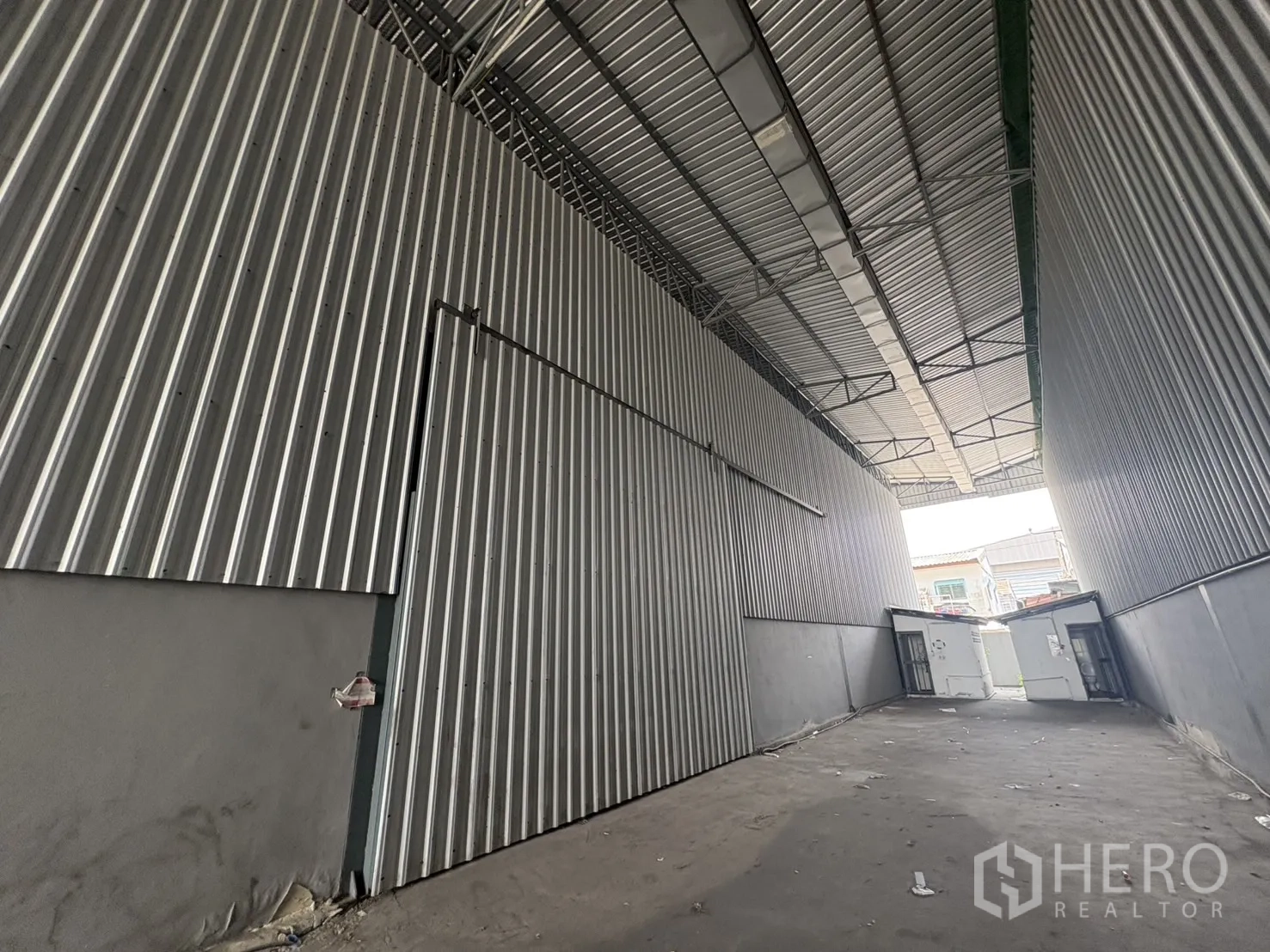 Warehouse for rent in Mueang Samut Prakan, Samut Prakan - Covered passage between warehouse bays with tall metal cladding and sliding access doors.