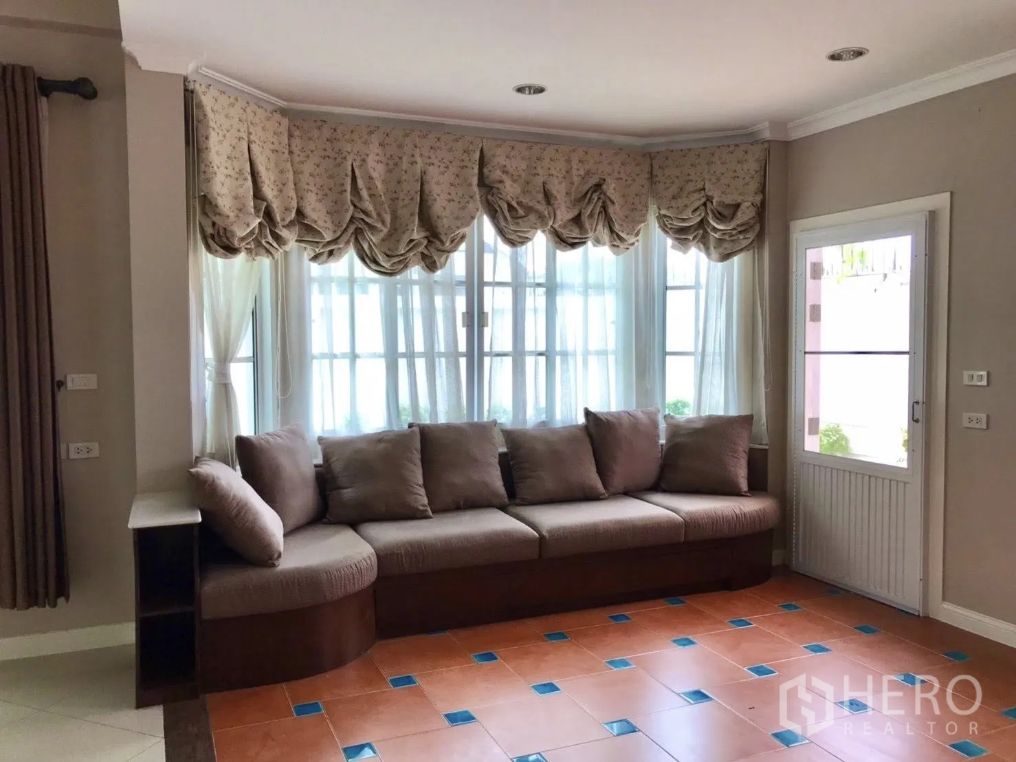 บ้านเดี่ยว for rent in Mueang Samut Prakan, Samut Prakan - มุมนั่งเล่นโซฟาสีน้ำตาลใต้ผ้าม่านจับจีบและประตูออกสวน
