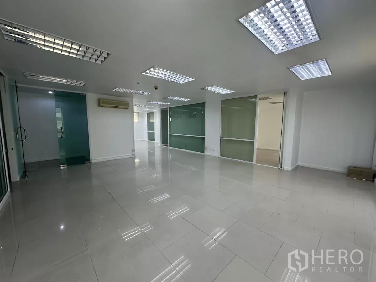 Office Space for rent in Huai Khwang, Bangkok - Large workspace with multiple glass meeting rooms and frosted partitions under grid ceiling lights.
