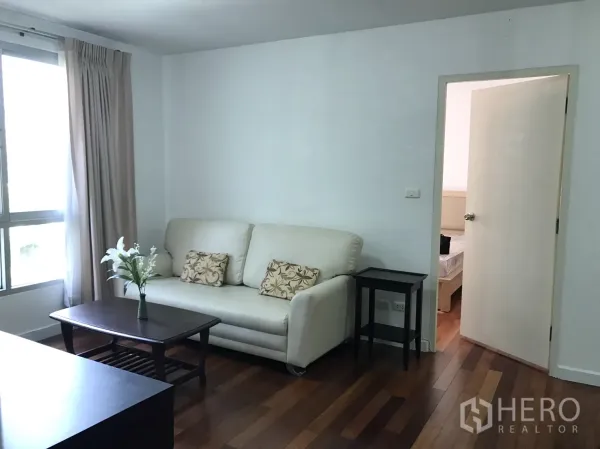 公寓 出租在Watthana, Bangkok - 温馨客厅，米色沙发与茶几，通向卧室的门。