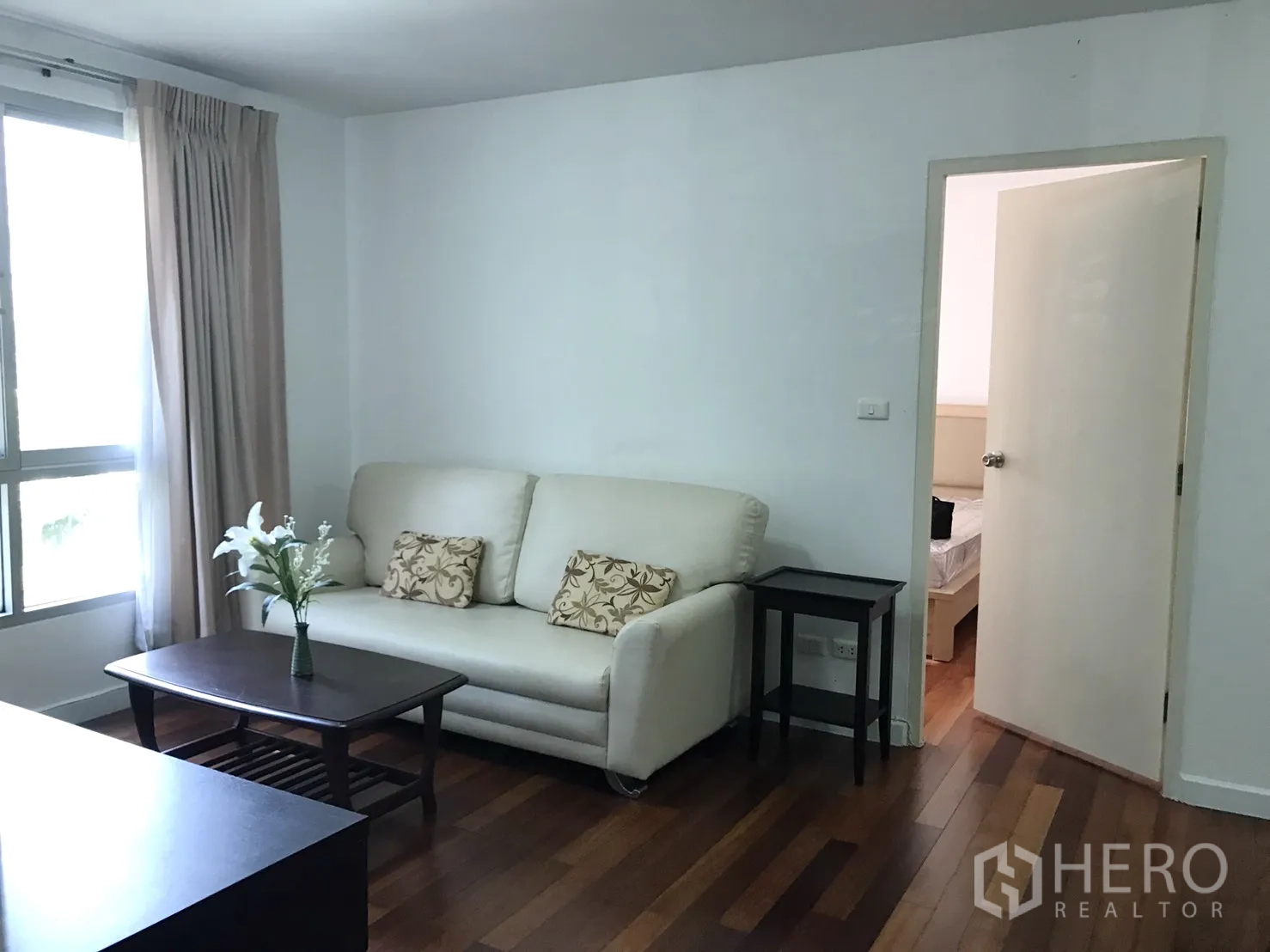 公寓 出租在Watthana, Bangkok - 温馨客厅，米色沙发与茶几，通向卧室的门。