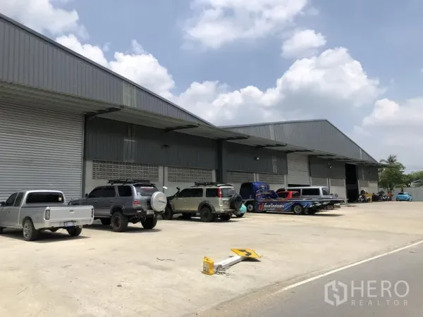 คลังสินค้า ให้เช่าในBang Kruai, Nonthaburi - แถวประตูโกดังหลายช่องมีชายคาขนถ่ายสินค้าและรถจอดบนทางกว้าง