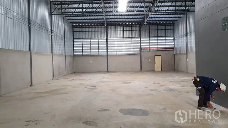 Warehouse for rent in Lam Luk Ka, Pathum Thani - Open warehouse hall with high roof, ventilation panels and bright strip lighting.