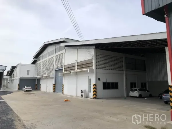 Warehouse for rent in Pathum Thani - Side view of the warehouse block with a covered loading bay, wide driveway, and rolling doors.