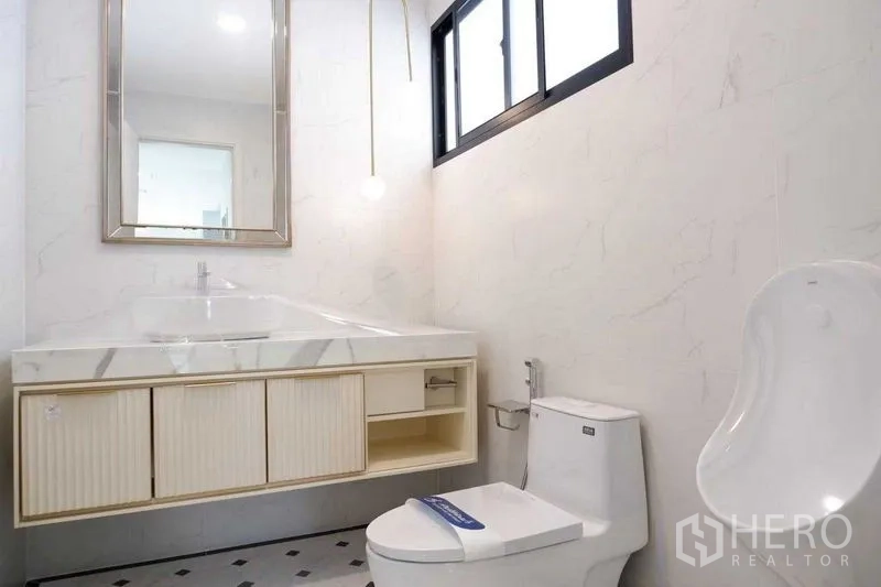 Detached House for sale in Saphan Sung, Bangkok - Powder room with marble-top vanity, window and sanitary fixtures.