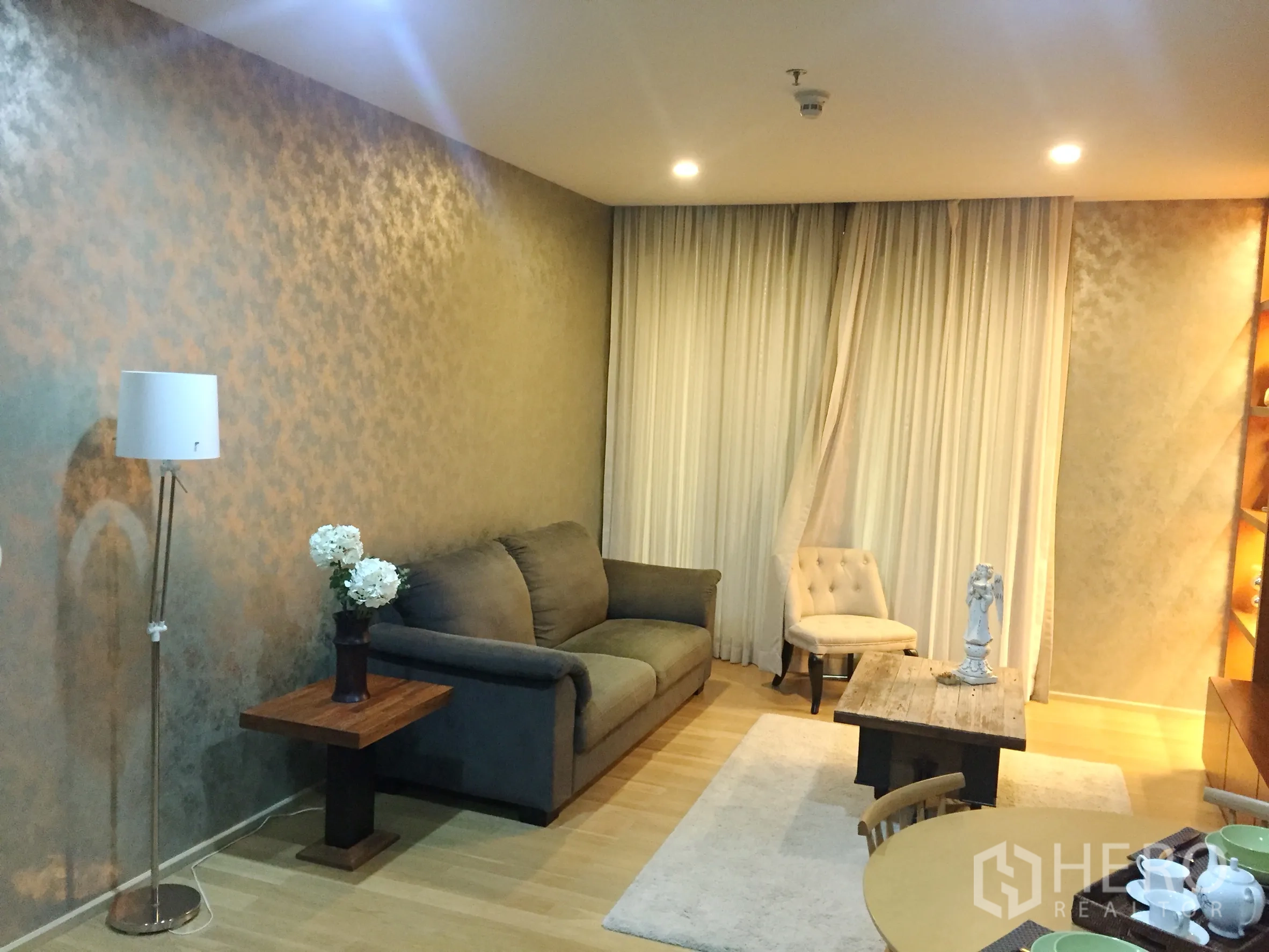 คอนโด ให้เช่าในWatthana, Bangkok - ห้องนั่งเล่นอบอุ่น โซฟาสีเทา โคมไฟ โต๊ะกลาง และผ้าม่านสูง พื้นไม้