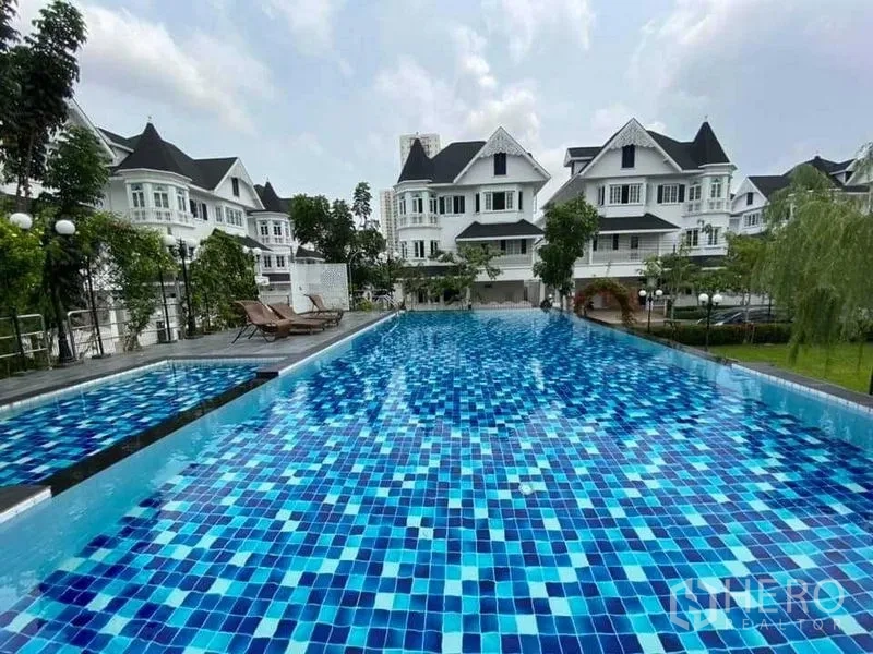 Townhouse for rent or sale in Mueang Samut Prakan, Samut Prakan - Large blue-tiled lap pool within landscaped residential estate.