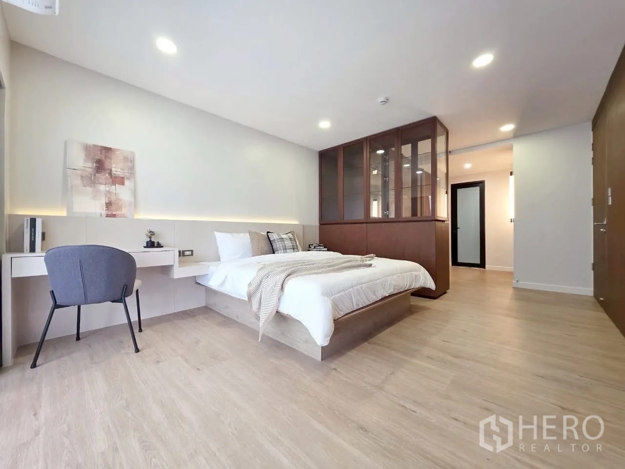 Condominium for rent in Sathon, Bangkok - Large bedroom with built-in desk, glass partition and wood floors.