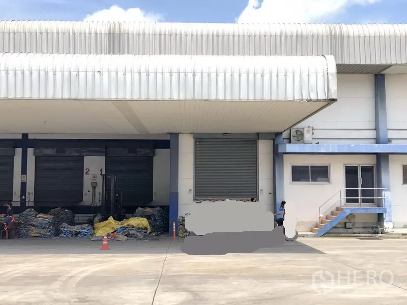 Warehouse for rent in Phra Nakhon Si Ayutthaya - Covered loading docks with roller shutter doors and a small office entrance with stairs.