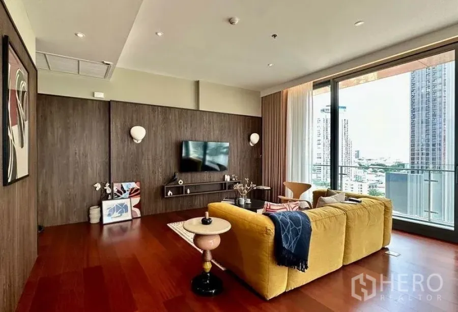 公寓 出租在Watthana, Bangkok - 客厅与阳台一体，木地板与充足自然光，远眺城市天际线。