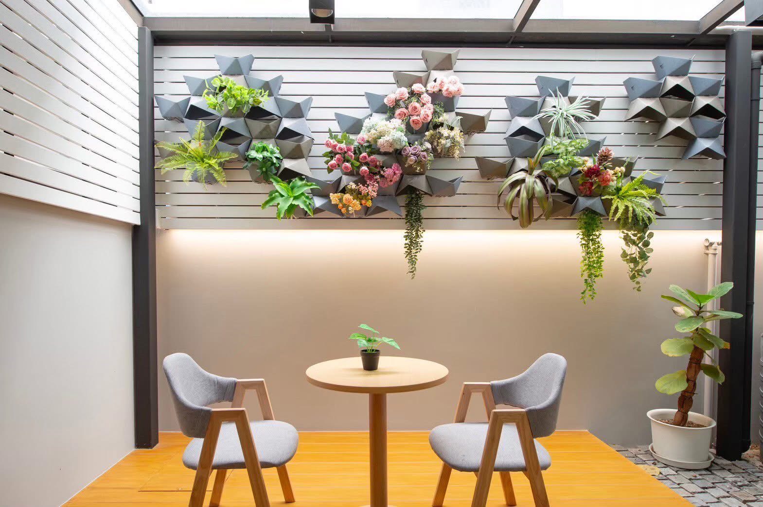 Townhouse for rent or sale in Lat Phrao, Bangkok - Covered patio with vertical garden planters, skylight roof and two chairs with a round table.