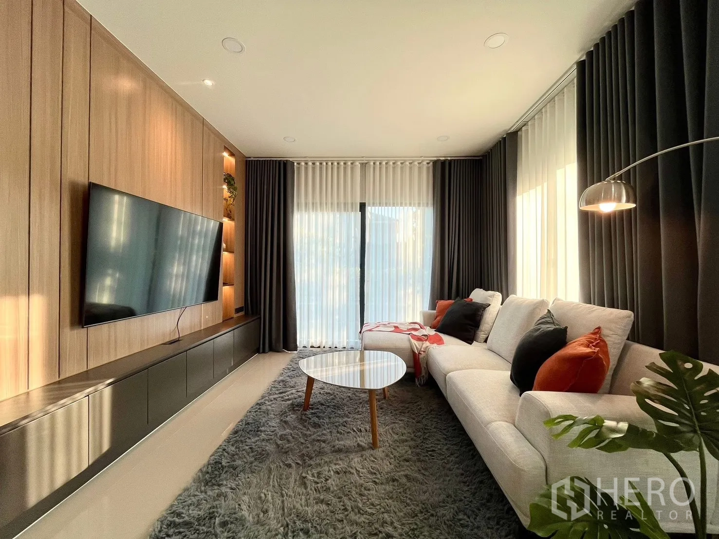 Detached House for rent in Bang Phli, Samut Prakan - Sunlit living space showcasing feature wall, shag rug, and floor lamp.