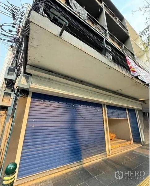 店屋 出租在Phaya Thai, Bangkok - 帕亚泰路边临街商铺外立面，蓝色卷闸门与上层阳台。