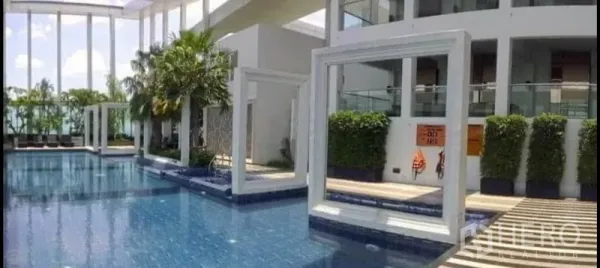 Condominium for sale in Phaya Thai, Bangkok - Condominium outdoor swimming pool with modern white frames, palm trees and sun deck seating.