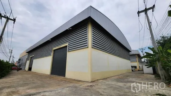Factory for rent in Ban Phaeo, Samut Sakhon - Factory exterior with corrugated metal cladding, large roller shutters and a wide driveway for container trucks.