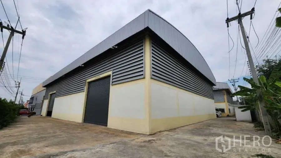 โรงงาน ให้เช่าในBan Phaeo, Samut Sakhon - ด้านนอกโรงงานกรุเมทัลชีท พร้อมประตูม้วนขนาดใหญ่ และทางวิ่งกว้างสำหรับรถคอนเทนเนอร์