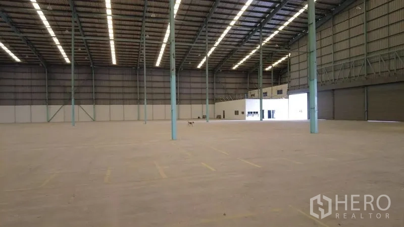 Warehouse for rent in Bang Phli, Samut Prakan - Expansive warehouse floor with roof lighting, roll-up doors and a small office block.