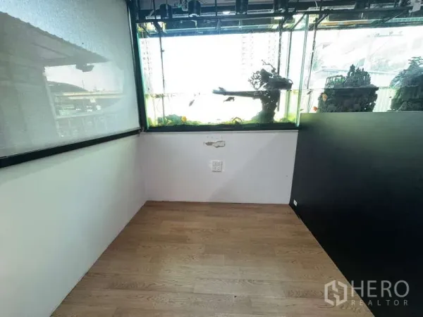 零售空间 出租在Ratchathewi, Bangkok - 临窗的大型水族箱与浅色木地板的角落空间。