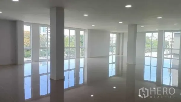 带办公室的家 出售在Huai Khwang, Bangkok - 明亮的开放式办公楼层，落地窗、亮面瓷砖与筒灯，可见绿景。