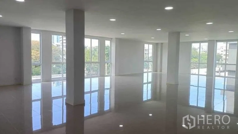 带办公室的家 出售在Huai Khwang, Bangkok - 明亮的开放式办公楼层，落地窗、亮面瓷砖与筒灯，可见绿景。