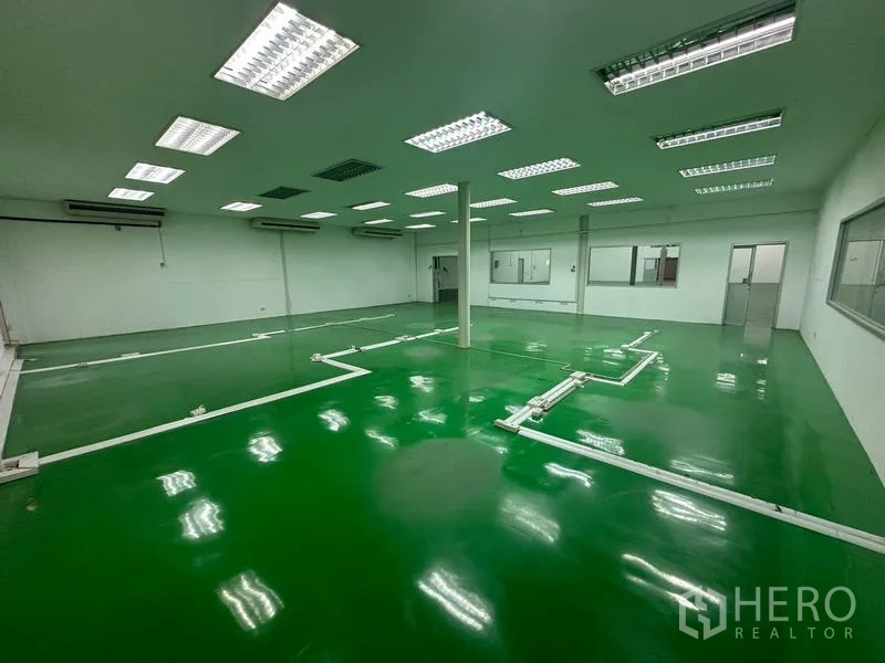 Warehouse for rent in Suan Luang, Bangkok - Production space showing windows, AC units, and epoxy flooring.