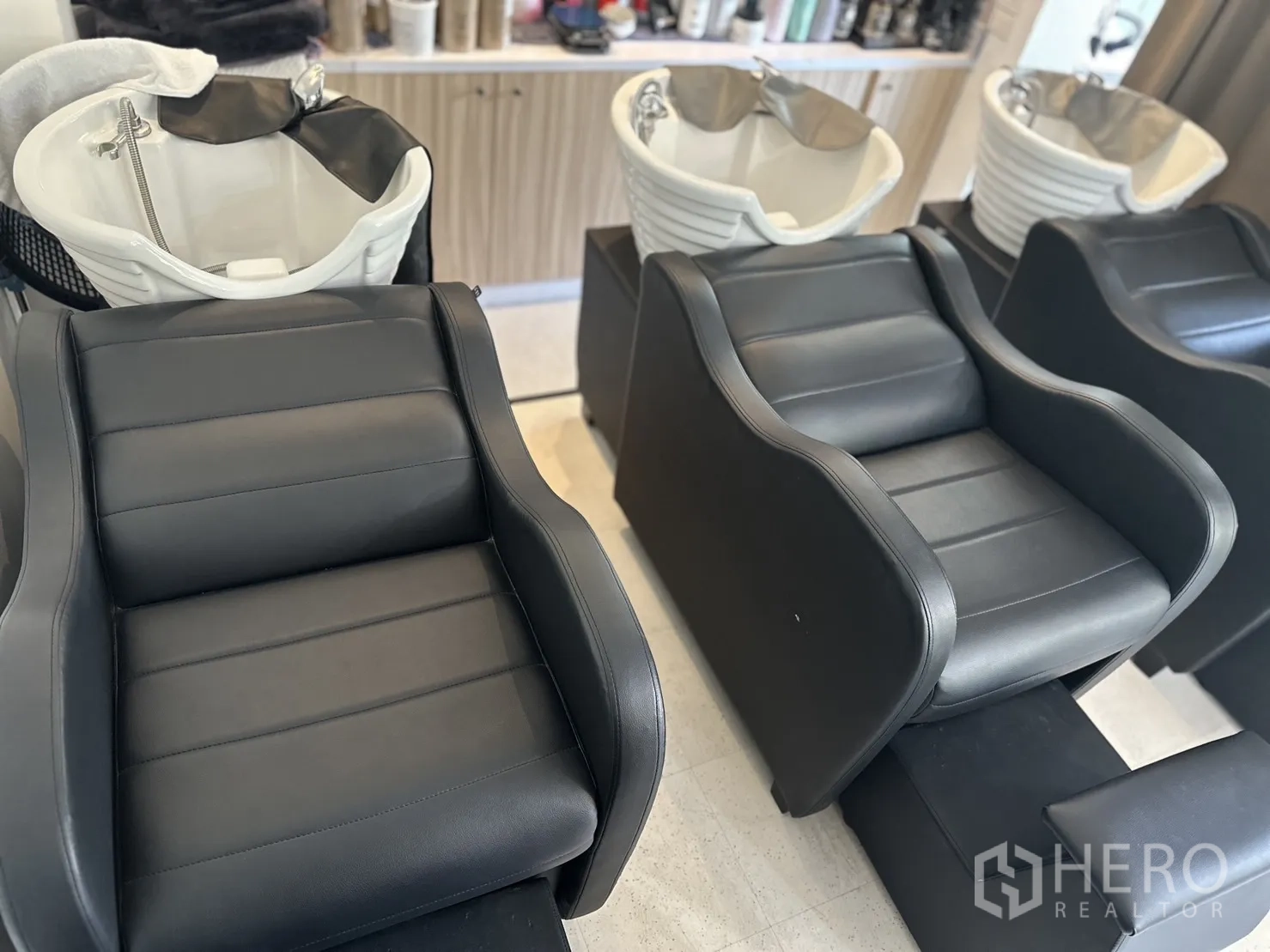 Retail Space for rent in Khlong Toei, Bangkok - Close-up of black shampoo chairs and white ceramic basins.