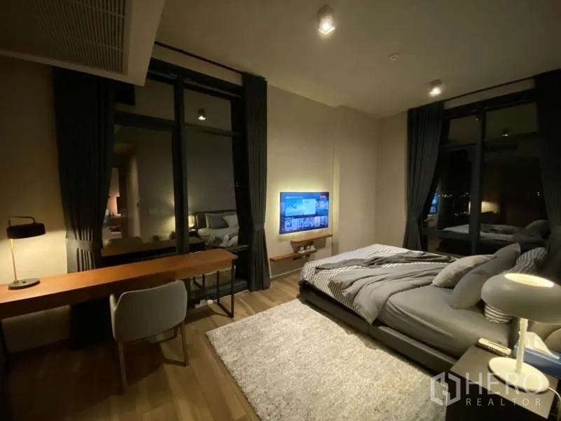 Condominium for rent or sale in Watthana, Bangkok - Spacious second bedroom featuring a work desk, wall‑mounted TV, and large windows.