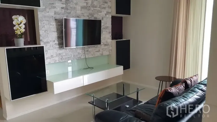 Condominium for rent in Ratchathewi, Bangkok - Modern living room with stone feature wall, wall-mounted TV, glass coffee table and leather sofa.