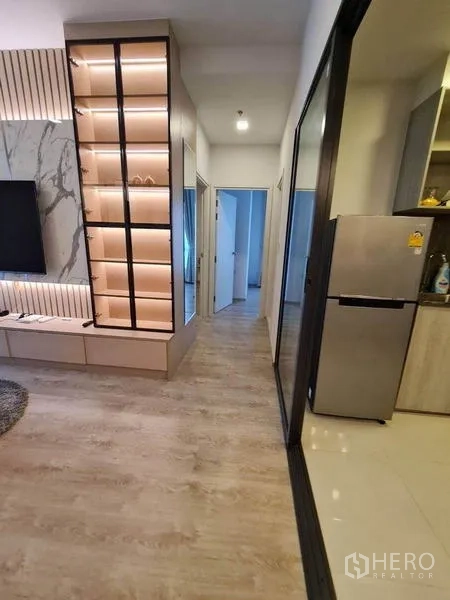 Condominium for rent - Hallway from living room to bedrooms featuring an illuminated display cabinet and view into the kitchen.