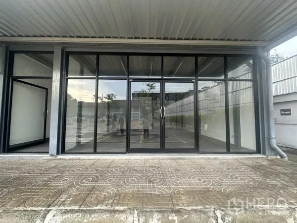 Retail Space for rent - Street-level retail storefront with full-height glass facade and a covered walkway, with on-site parking in front.
