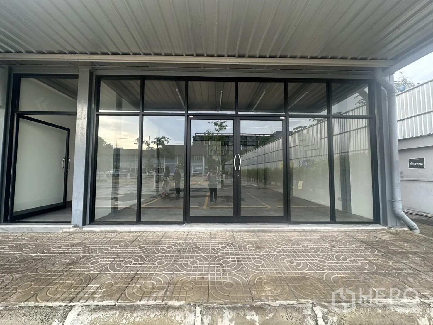 Retail Space for rent - Street-level retail storefront with full-height glass facade and a covered walkway, with on-site parking in front.