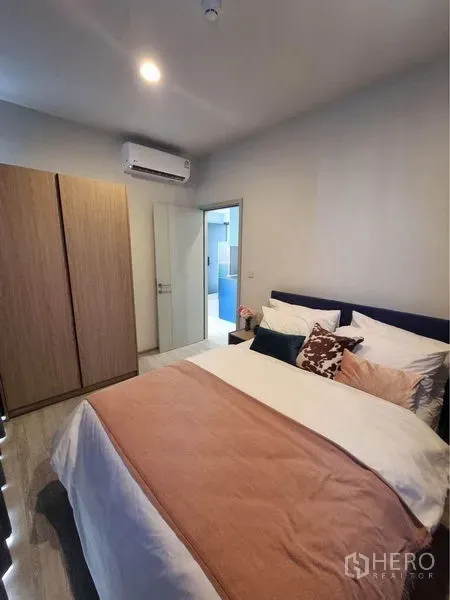 公寓 出租在Watthana, Bangkok - 温馨卧室，双人床、衣柜与空调，带通往浴室的门。