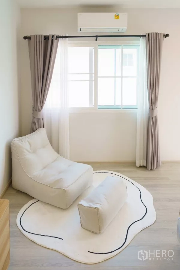Detached House for rent in Bang Phli, Samut Prakan - Reading corner with white lounge chair and footrest on a soft rug.