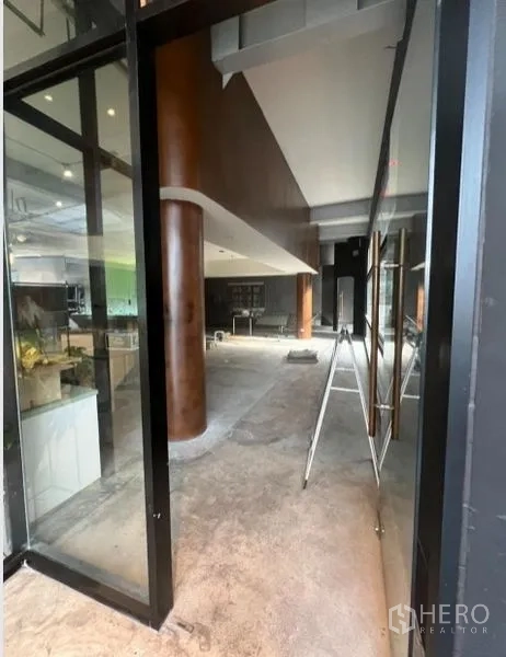 Retail Space for rent in Watthana, Bangkok - Glass entrance and shopfront leading into a spacious unit with wood-clad columns.