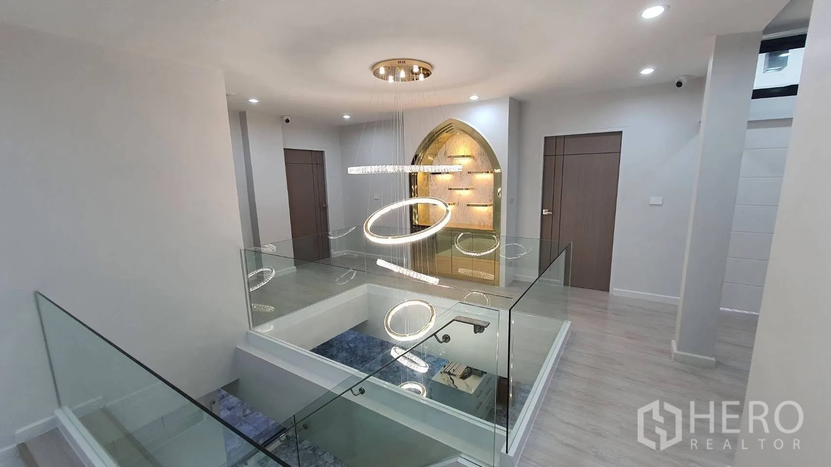 Detached House for rent in Lat Phrao, Bangkok - Upper landing with glass balustrade and modern ring chandelier.
