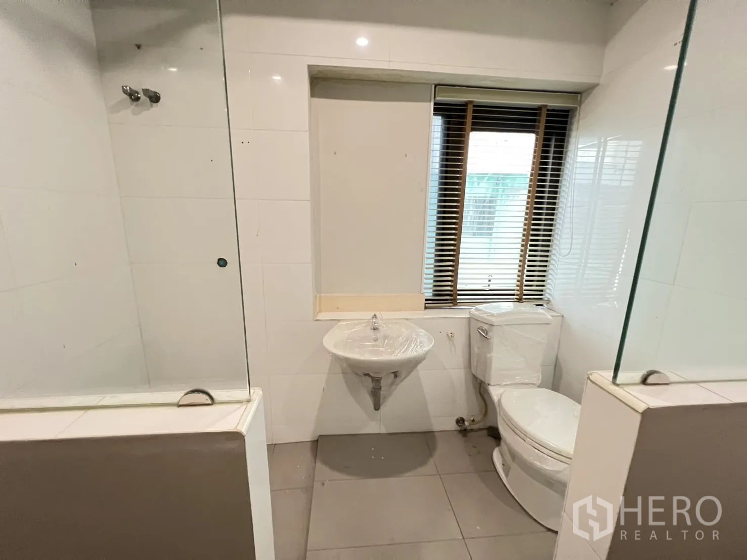 Shophouse for rent in Bang Rak, Bangkok - Bathroom with window, sink, toilet and glass shower partitions.