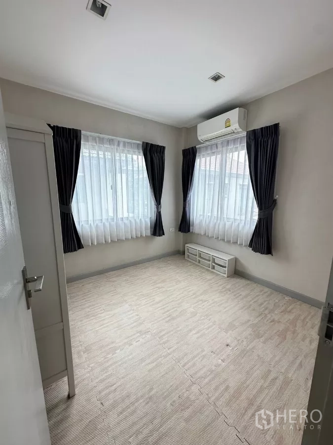 Detached House for rent in Saphan Sung, Bangkok - Empty corner bedroom with two windows, air-conditioner and curtains.
